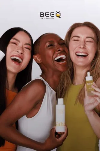 Tre donne sorridenti con prodotti cosmetici, campagna BeeQ